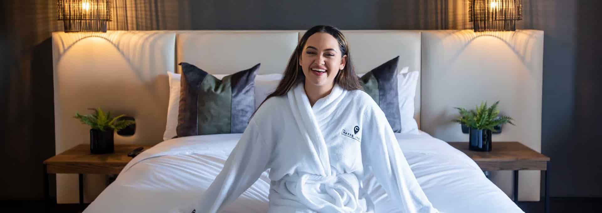 Happy woman sitting on the bed in The Capital Zimbali room